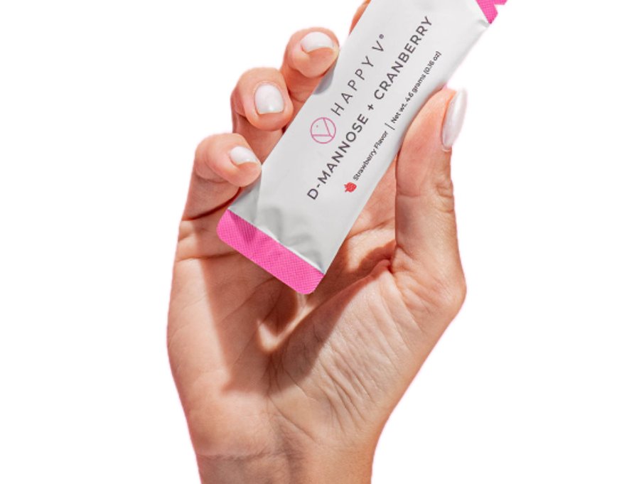 Hand holding a Happy V D-Mannose and Cranberry supplement packet