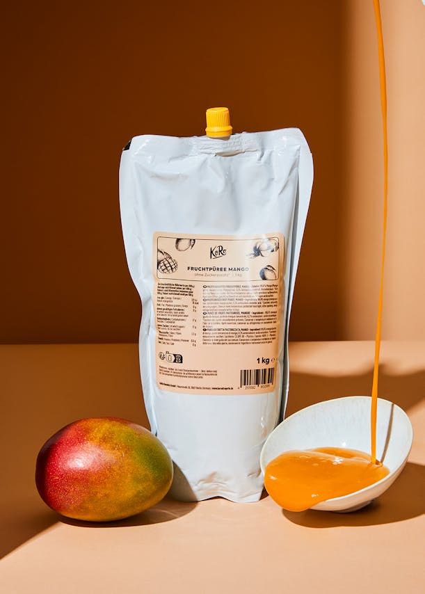 Beutel mit Mango-Fruchtpüree neben einer Mango