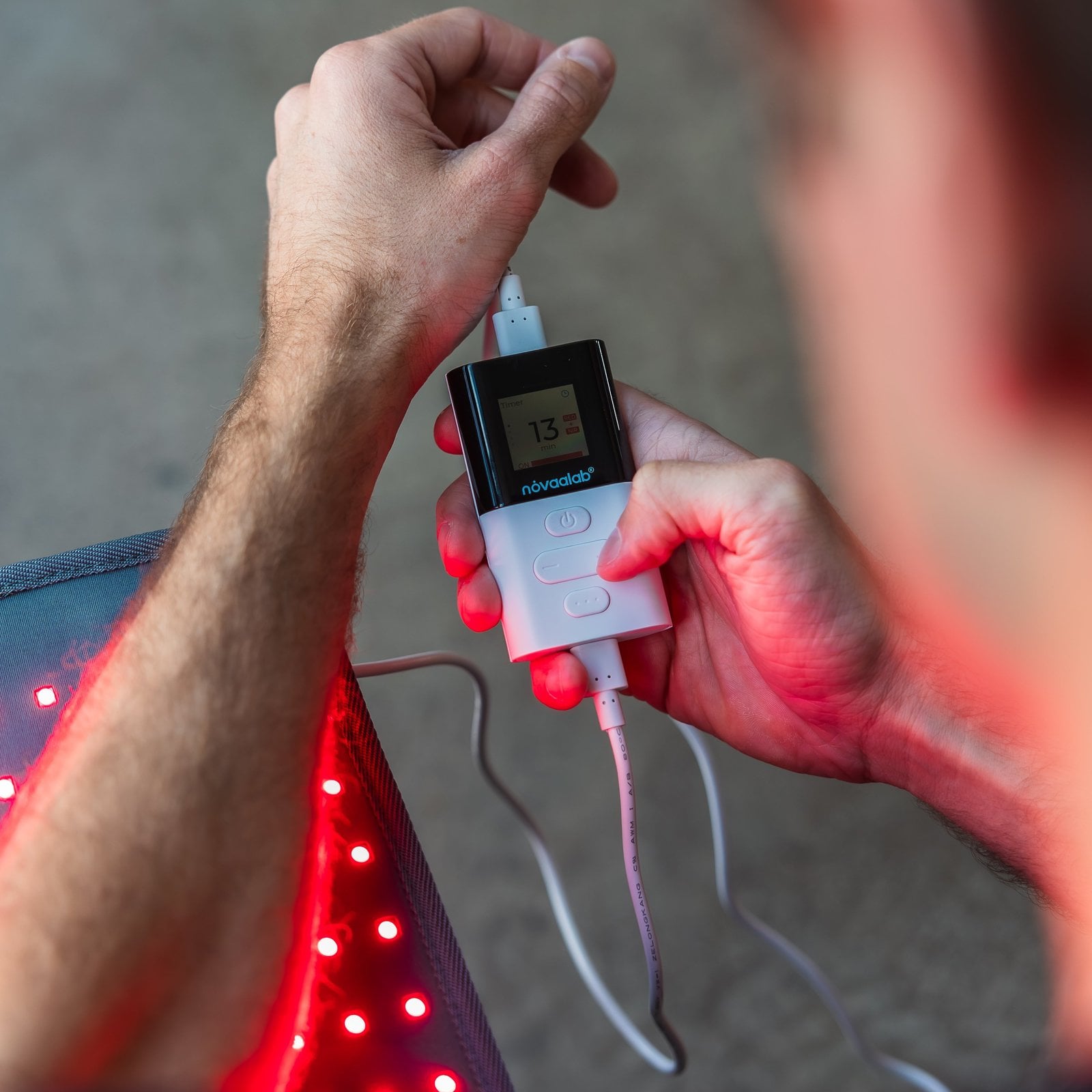Seated person holding the NOVAALAB LLC light pad for targeted therapy