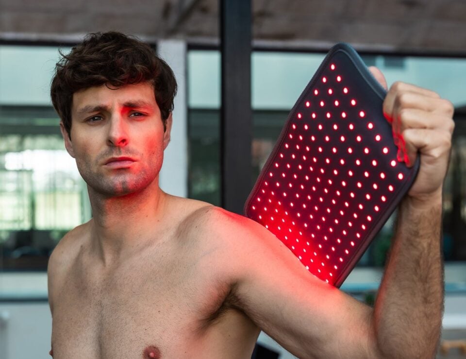 Person holding the NOVAALAB LLC light pad over a shoulder during a recovery session