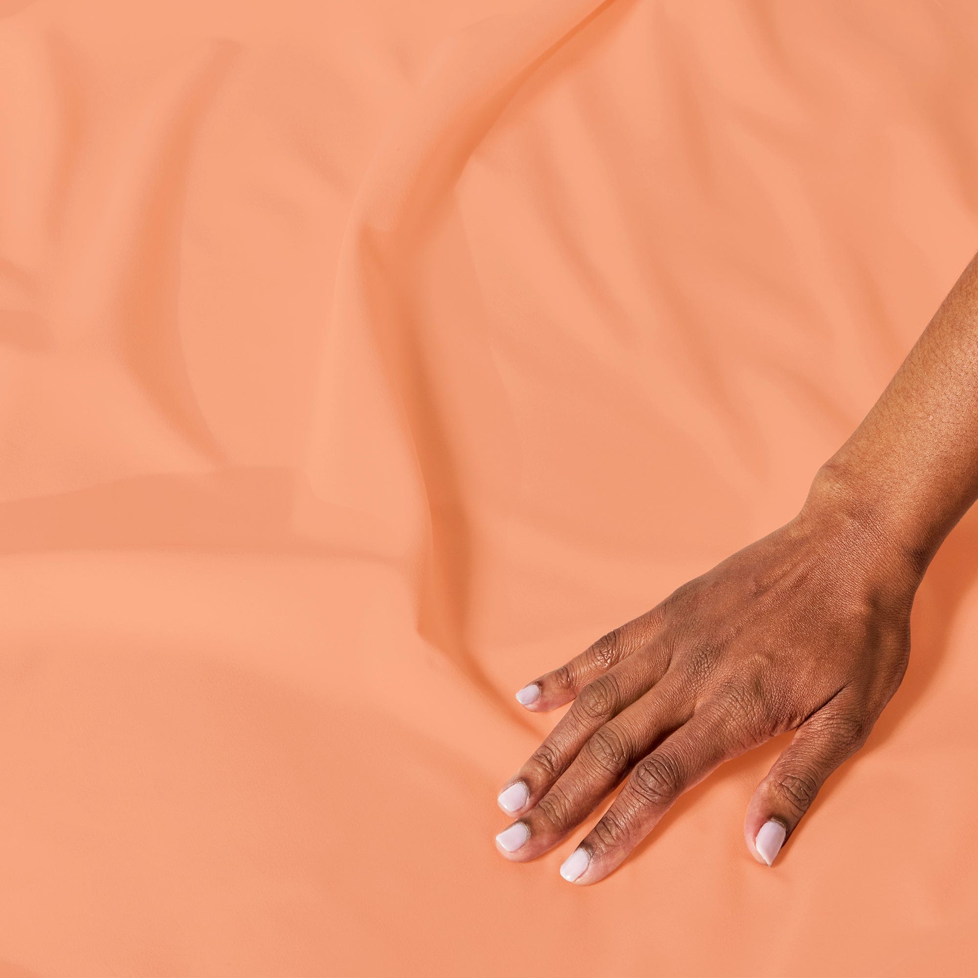 A hand smoothing PeachSkinSheets fabric