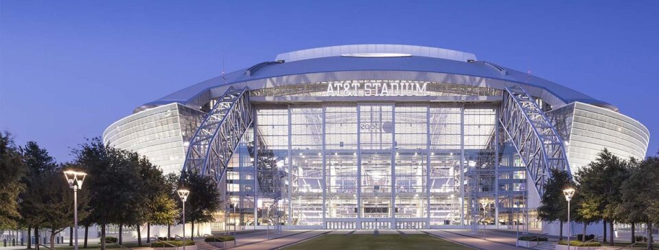 AT&T Stadium exterior illuminated against the evening sky