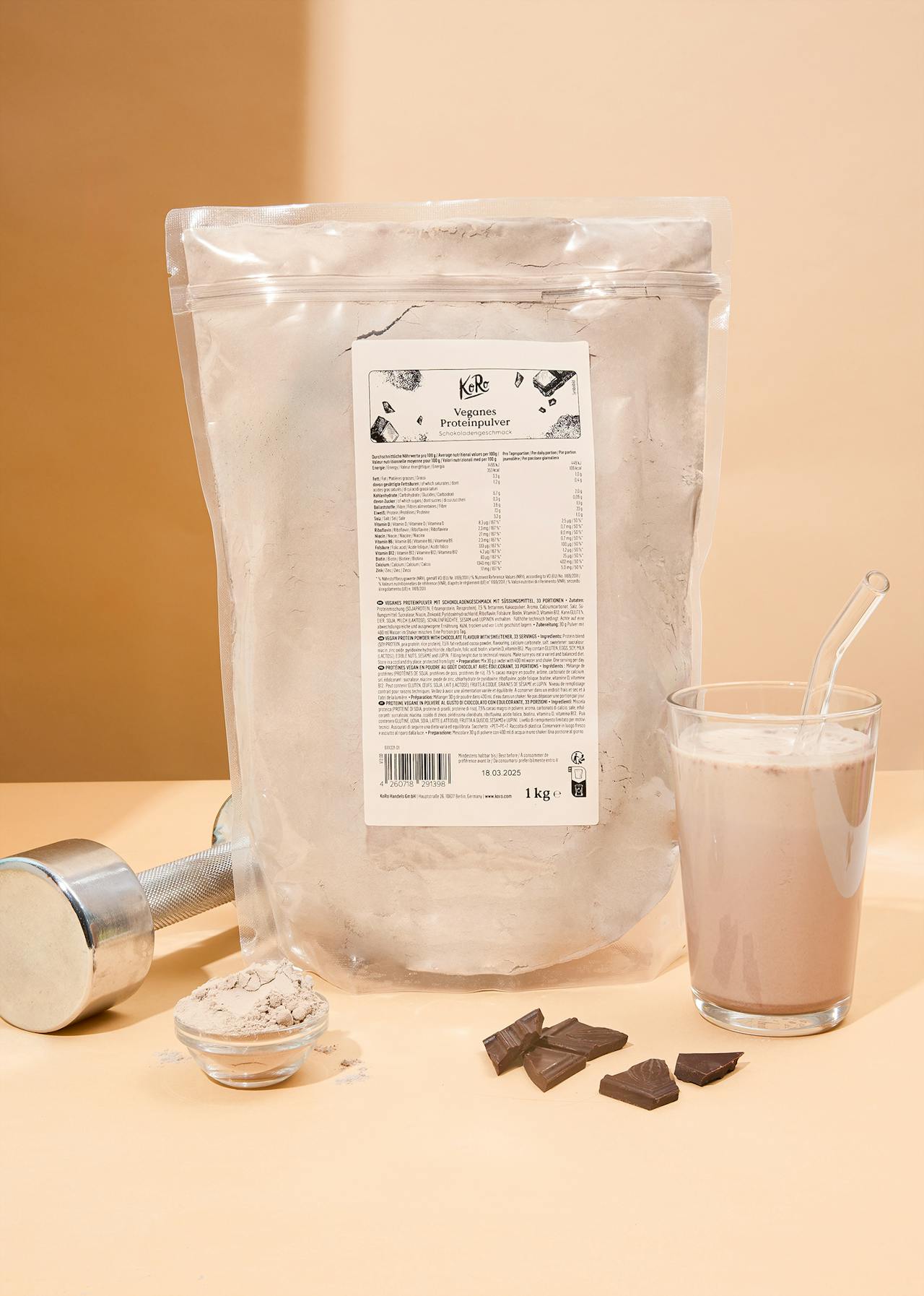 Packung veganes Proteinpulver Schokolade neben einem Glas und Schokoladenstücken