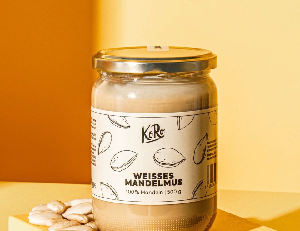 Glas mit weißem Mandelmus neben Brot auf einem Tisch
