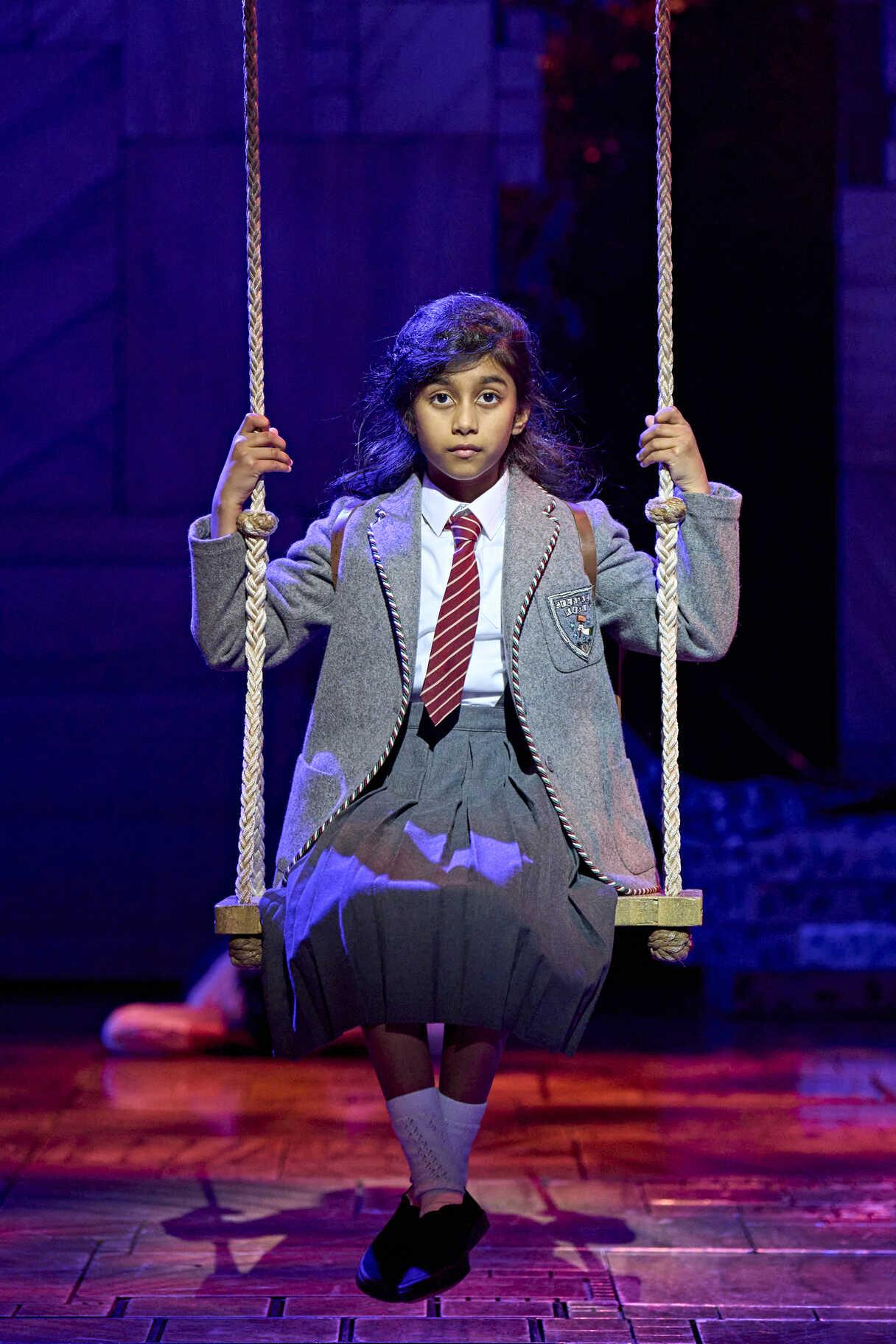 A young performer swinging across the Matilda stage