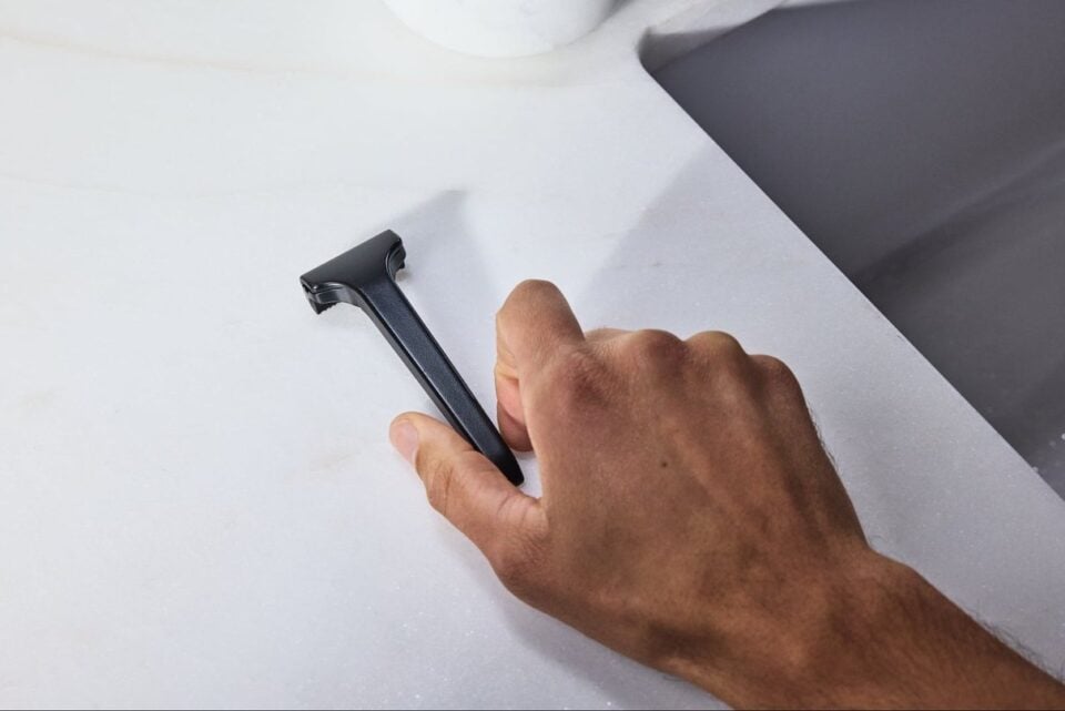 A hand holding a black Supply razor