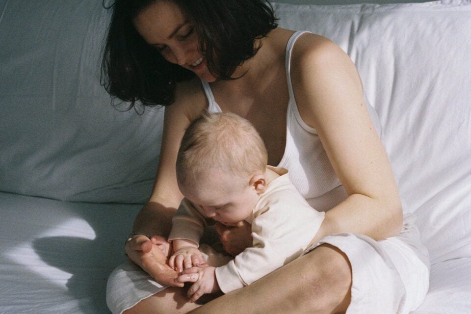 Mother sitting on a bed with her infant