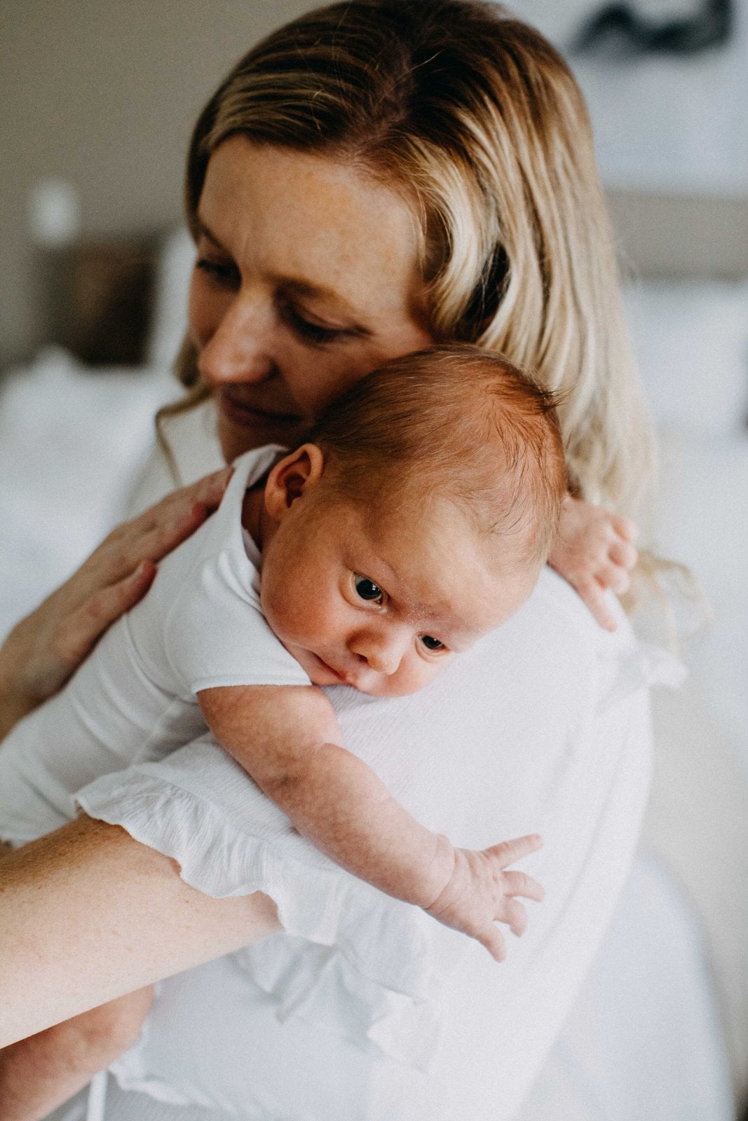 Mother leaning over her baby on a bed