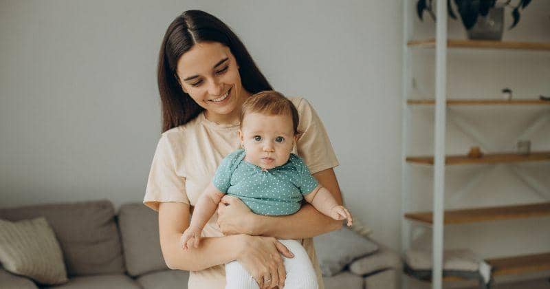 Mother leaning over her baby on a bed