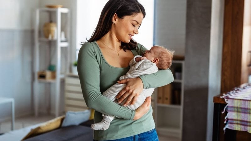 Mother leaning over her baby on a bed
