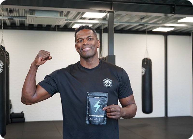Kickboxing champion holding a Zapply supplement pouch in a training gym